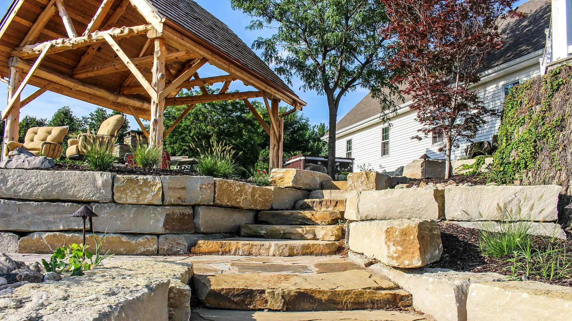 A beautiful backyard patio, pergola, retaining wall, and stone steps built behind a home in Douglas County, NE. 