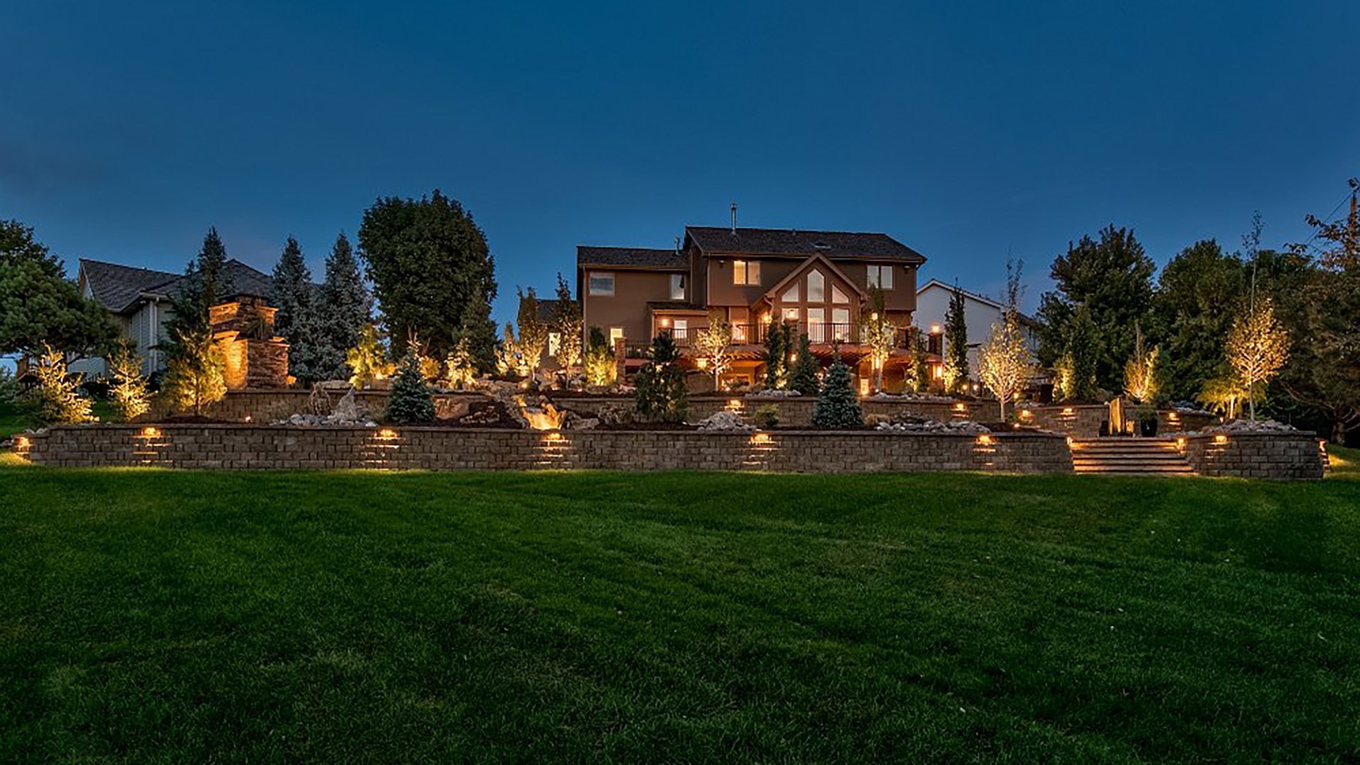 A grand home and landscape lit up at nighttime in La Vista, NE.