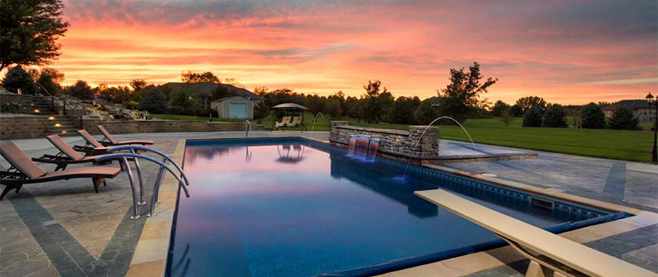 Beautiful custom pool and outdoor living area under a sunset in Bennington, NE.