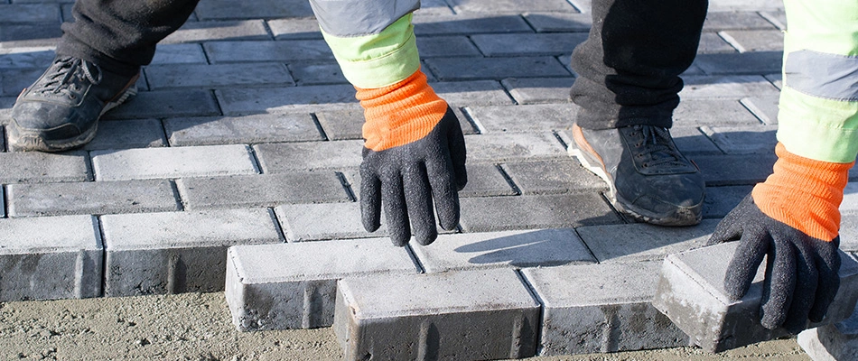 Person constructing a hardscape using the running bond paver pattern in Waterloo, NE.