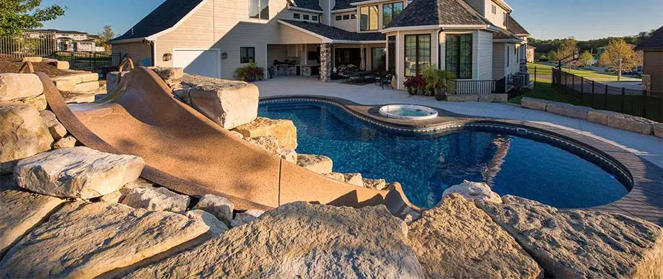 Custom pool with a slide and outdoor living space built in Gretna, NE.