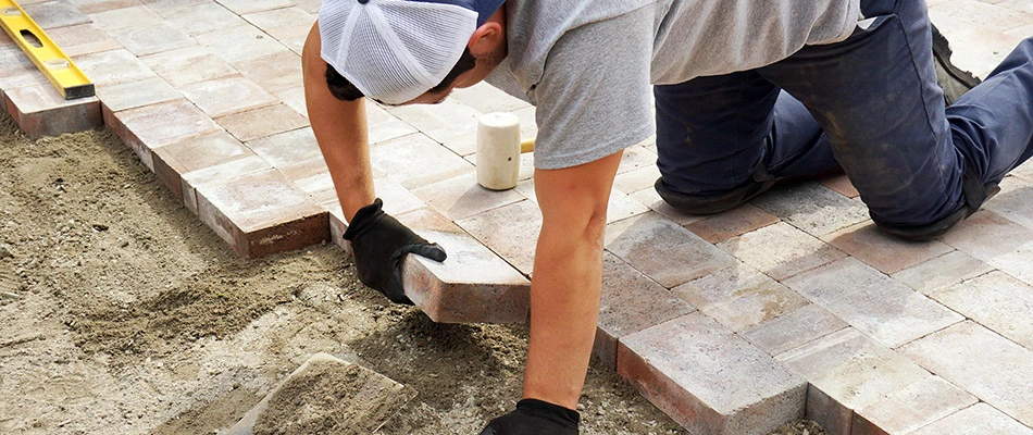 Content landscape professional installing a driveway using brick pavers near Gretna, NE.