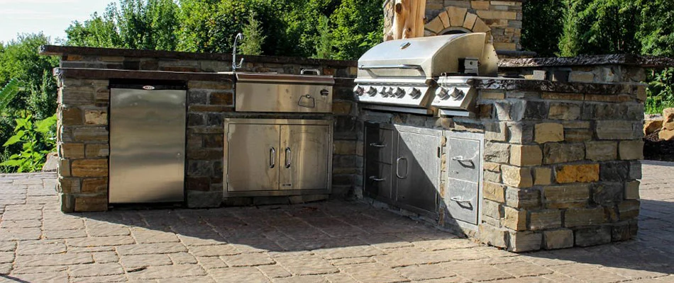 A natural stone outdoor kitchen with silver appliances in Papillion, NE.