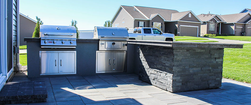An outdoor kitchen with a stone counter and patio in Omaha, NE.