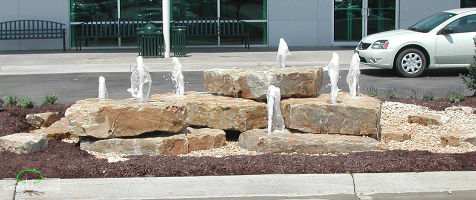 A water fountain built out of rocks in front of a commercial building in Omaha, NE.
