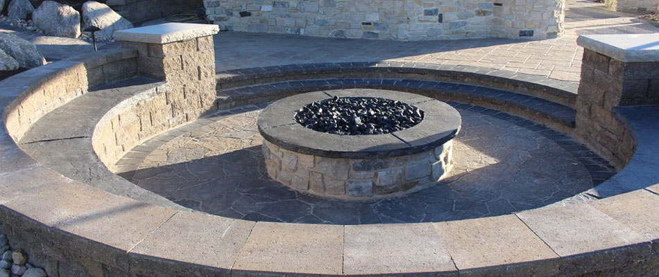 A round stone fire pit surrounded by seating walls in Elkhorn, NE.