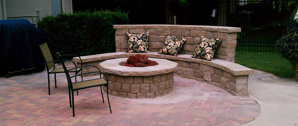 A stone seating wall with pillows built around a patio and fire pit in Waterloo, NE.