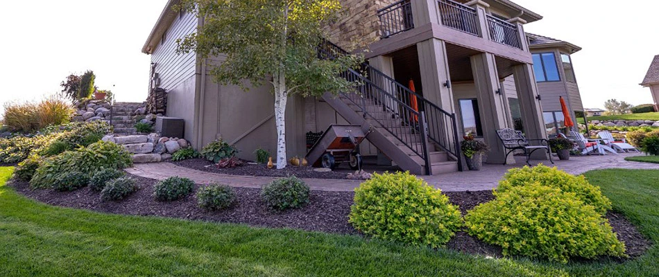 A long landscape bed alongside a pathway next to a home in Valley, NE.